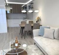 Nappali egy kétszobás lakásban, fa mintázatú padlóval, kanapéval és étkezőasztallal.