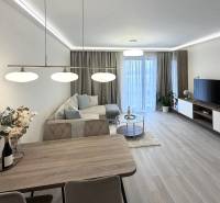 Nappali étkezőasztallal, kanapéval és fa dekorációjú padlóval egy kétszobás lakásban.