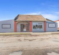 Kereskedelmi helyiségek Okoč városában kirakatokkal és ferde tetővel.