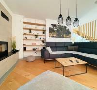 Egy villa belső tere fa dekorációjú padlóval, kényelmes kanapéval és beépített kandallóval.