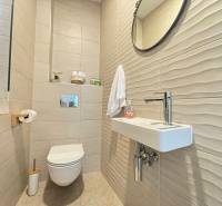 Fürdőszoba a villában csempével, tükörrel és egyszerű mosdóval.