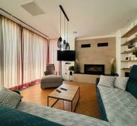 Nappali a villában kandallóval, TV-vel, fa hatású padlóval és kényelmes ülőgarnitúrával.