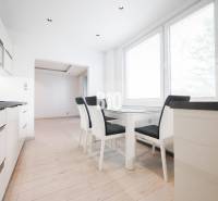 Konyha egy háromszobás lakásban, étkezőasztallal és fa dekor padlóval.