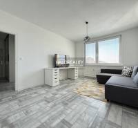 Nappali egy kétszobás lakásban, fa dekoros padlóval és szürke kanapéval.