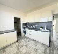 Konyha egy kétszobás lakásban fehér szekrényekkel és fa mintázatú padlóval.