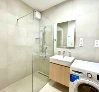 Fürdőszoba zuhanyzóval és mosógéppel egy kétszobás lakásban.