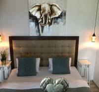 Hálószoba stílusos világítással és elefántképpel egy kétszobás lakásban.