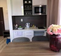 Konyha egy kétszobás lakásban fehér szekrényekkel és mikrohullámú sütővel.