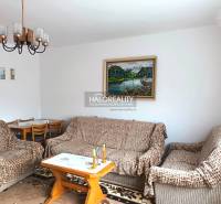 Családi ház nappalija kanapéval, képpel és étkezőasztallal.