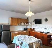 Konyha családi házban fa konyhabútorral és étkezőasztallal.