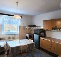 Családi ház konyhája étkezőasztallal és fa szekrényekkel.