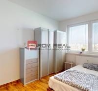 Világos hálószoba fabútorokkal és fa hatású padlóval egy 4 szobás lakásban.