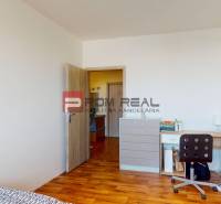 Szoba egy négy szobás lakásban, fa dekoros padlóval, íróasztallal és komóddal.