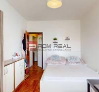 Hálószoba egy 4 szobás lakásban fa dekor padlóval, ággyal és szekrénnyel.