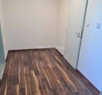 Irodai folyosó fa mintázatú padlóval és fehér falakkal.