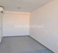 Svetlé kancelárske priestory fehér falakkal és ablakkal, fa mintázatú padlóval.