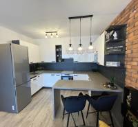 Konyha egy kétszobás lakásban, fa dekor padlóval és téglafal burkolattal.