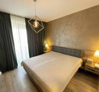 Hálószoba ággyal, fa dekoros padlóval és függönyökkel egy kétszobás lakásban.