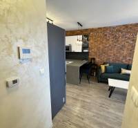 2 szobás lakás belső tere fa dekor padlóval, téglafallal és konyhasarokkal.