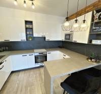 Konyha egy kétszobás lakásban fehér szekrényekkel és fa mintázatú padlóval.