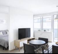 Világos nappali egy kétszobás lakásban, televízióval és étkezőasztallal.