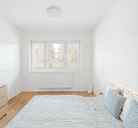 Világos hálószoba egy 4 szobás lakásban, fa dekor padlóval és dekoratív párnákkal.