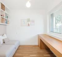 Világos szoba fa mintás padlóval, kanapéval és nagy ablakokkal.