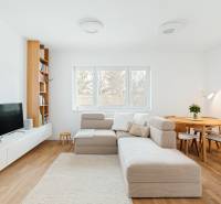 Nappali kanapéval, TV-vel, könyvespolccal és étkezőasztallal, fa dekoros padlóval.