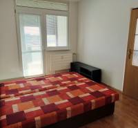 Hálószoba egy háromszobás lakásban, ággyal és fa dekorációjú padlóval.