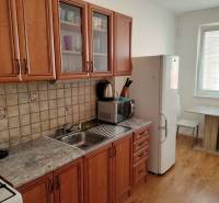 Konyha egy háromszobás lakásban, fa dekor padlóval és fa bútorokkal.