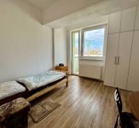 Garzonlakás ággyal, asztallal, szekrénnyel és fa dekor padlóval.