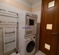 Fürdőszoba egy kétszobás lakásban mosógéppel és szárítógéppel, fehér radiátor a falon.