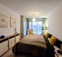 Hálószoba ággyal, dekoratív párnákkal és komóddal egy kétszobás lakásban.