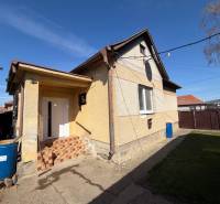 Családi ház Belincon előkerttel és beton udvarral a kék ég alatt.