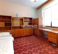 Szoba szőnyegpadlóval, fa bútorokkal egy családi házban.