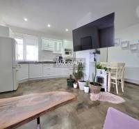 Konyha családi házban fehér bútorokkal, dekoratív növényekkel és fa dekoros padlóval.