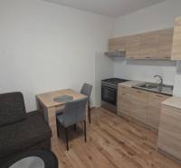 Konyha egy egyszobás lakásban fa dekorációjú padlóval és bútorokkal.