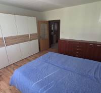 Hálószoba egy egyszobás lakásban fa dekor padlóval és praktikus bútorokkal.