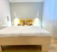 Világos hálószoba egy kétszobás lakásban színes párnákkal az ágyon.