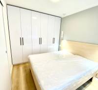 Hálószoba franciaággyal, fehér szekrénnyel és fa mintázatú padlóval egy kétszobás lakásban.