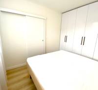 Hálószoba egy kétszobás lakásban, ággyal és nagy beépített szekrénnyel.