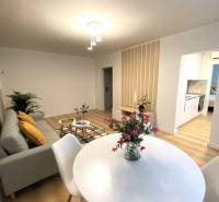 Ebédlő egy kétszobás lakásban, fehér asztallal és fa mintázatú padlóval.