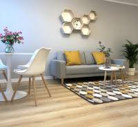 Nappali egy kétszobás lakásban fa mintázatú padlóval, szürke kanapéval és dekoratív hatszögekkel.