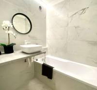 Fürdőszoba egy kétszobás lakásban káddal, tükörrel és virágdekorációval.