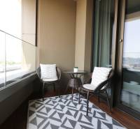 Erkély egy 2 szobás lakásban rattan bútorokkal és kilátással a városra.