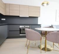 Két szobás lakás konyhája fa mintázatú padlóval és stílusos asztallal.