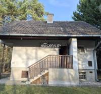 Házikó Borsky Svätý Jurban az erdő közepén, erkéllyel és ferde tetővel.