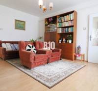 Családi ház nappalija kanapéval, fotelekkel és könyvespolccal, fa dekorációjú padlón.