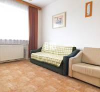 Nappali egy családi házban kanapéval és fotellel, szőnyeg.