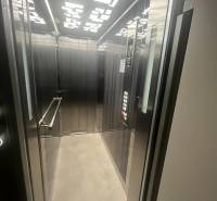 Egy modern világítással és fém panelekkel ellátott épület liftje.
